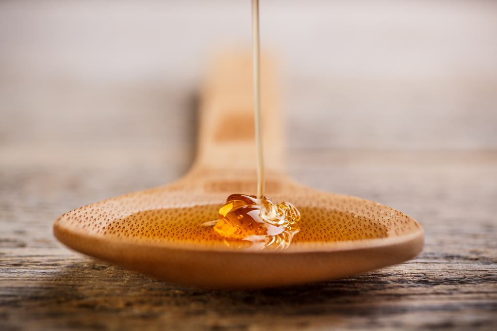 Wooden spoon with wild honey falling into it